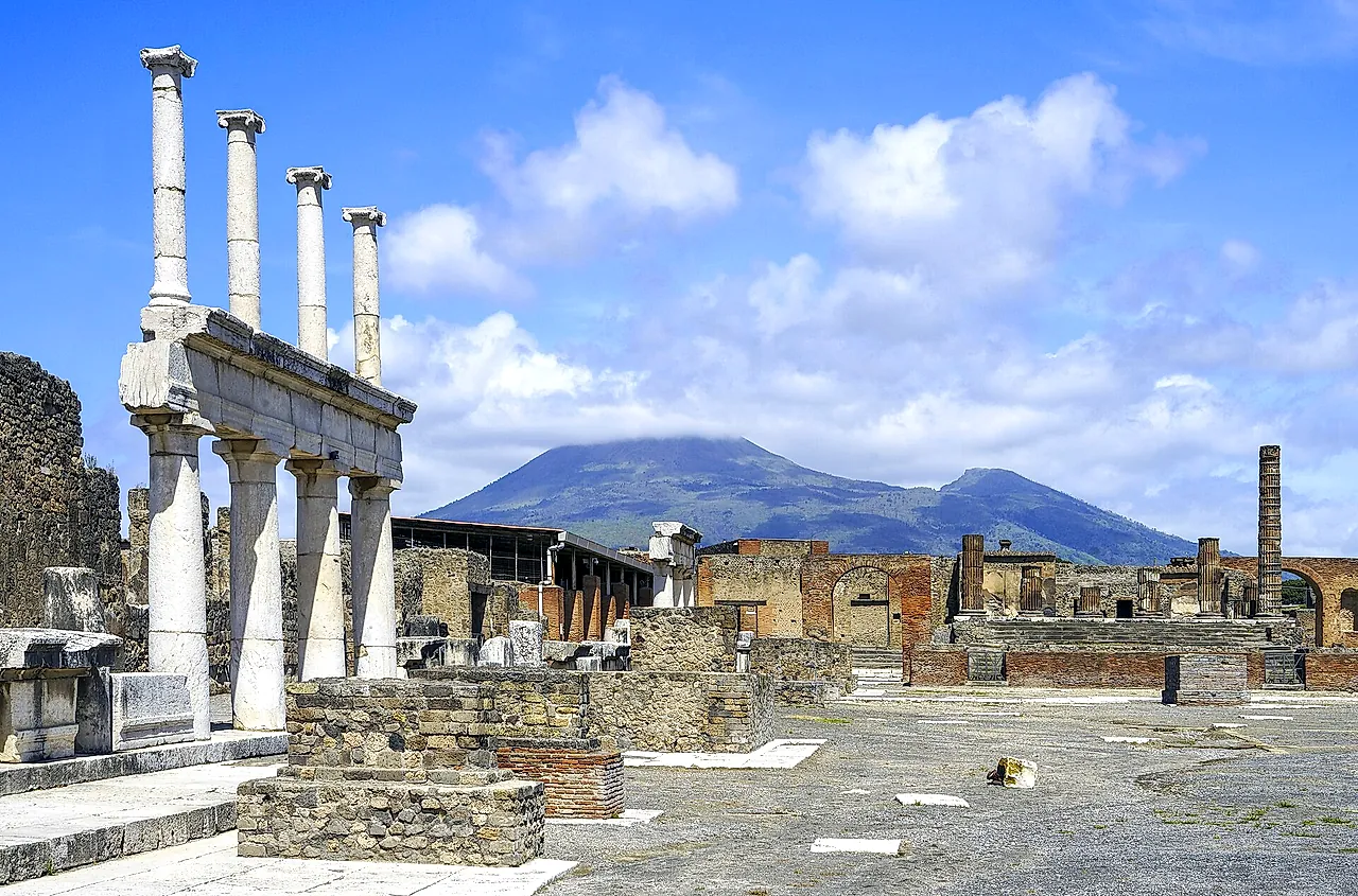 The Forum of Pompeii with the white colonnade in the foreground and Mount Vesuvius rising behind the ruins