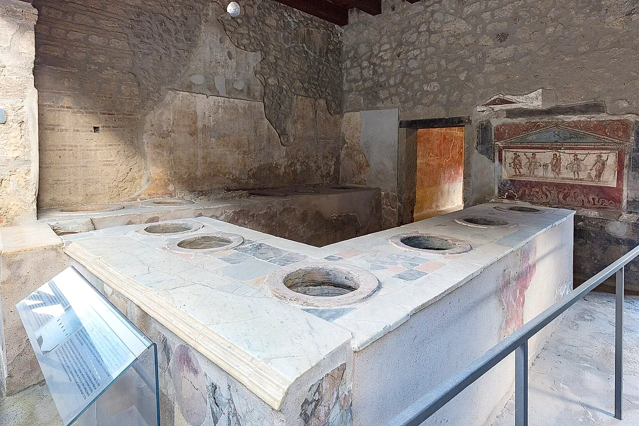 The L-shaped counter of the Thermopolium of Vetutius Placidus in Pompeii, with a painted shrine behind