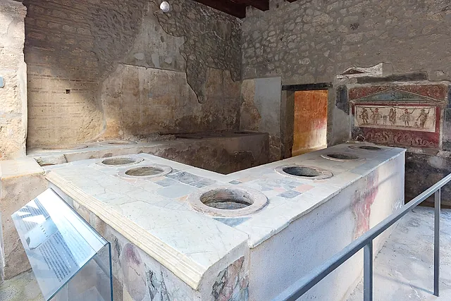The L-shaped counter of the Thermopolium of Vetutius Placidus in Pompeii, with a painted shrine behind