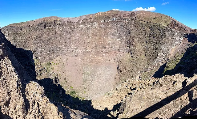 The crater of Mount Vesuvius with its layered walls under a blue sky