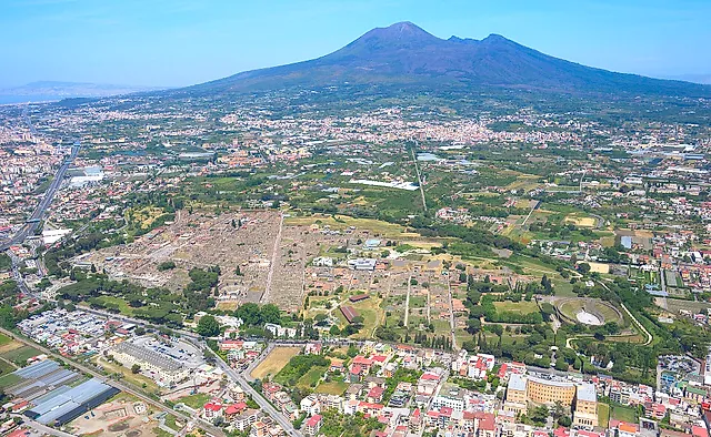 Aerial view of the excavations of Pompeii and Mount Vesuvius rising behind the plain